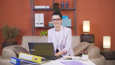 Home-office-worker-young-woman-smiling-at-camera.